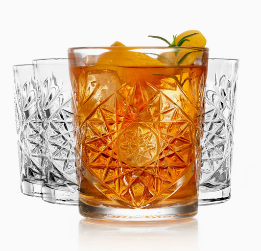 Decorative glass with a cocktail and garnish, surrounded by other glasses on a white background