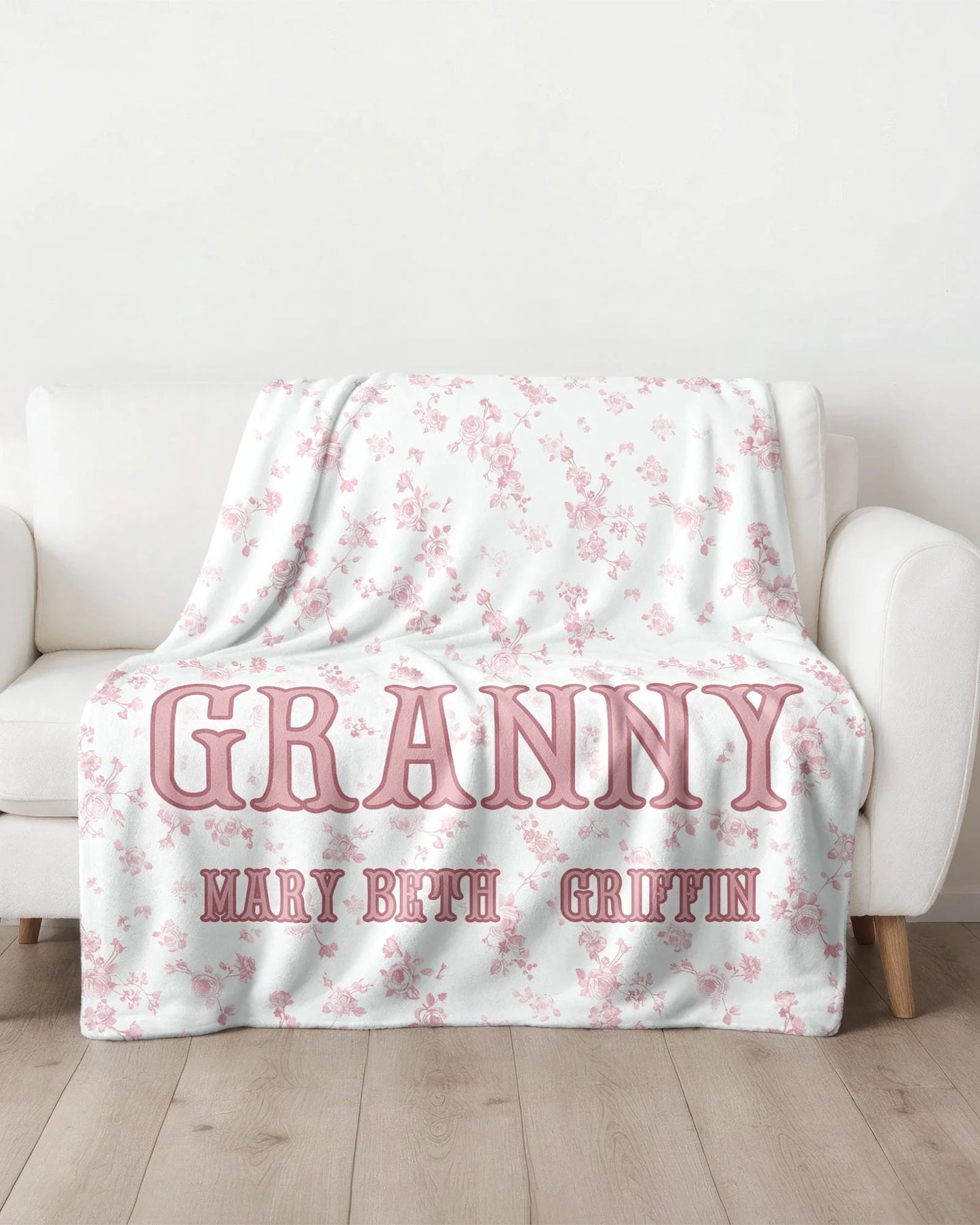 Floral-patterned blanket with 'GRANNY' and names on a white couch.