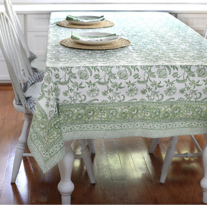 Dining table with a green and white patterned tablecloth on a wooden floor.