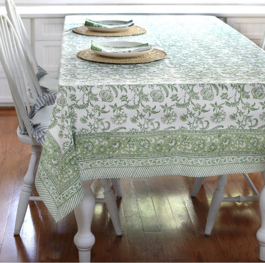 Dining table with a green and white patterned tablecloth on a wooden floor.