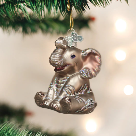 Decorative elephant ornament hanging on a Christmas tree with lights in the background
