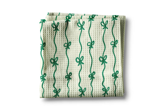 Waffle-textured towel with green bow pattern on a white background