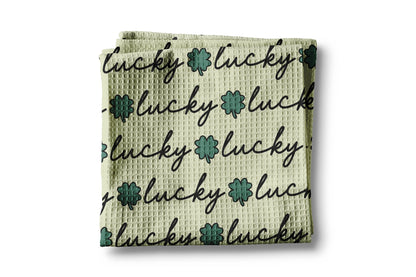 Waffle-textured towel with 'lucky' text and floral designs on a white background