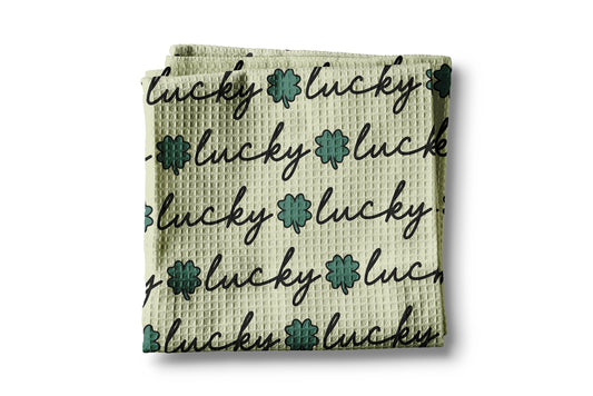 Waffle-textured towel with 'lucky' text and floral designs on a white background