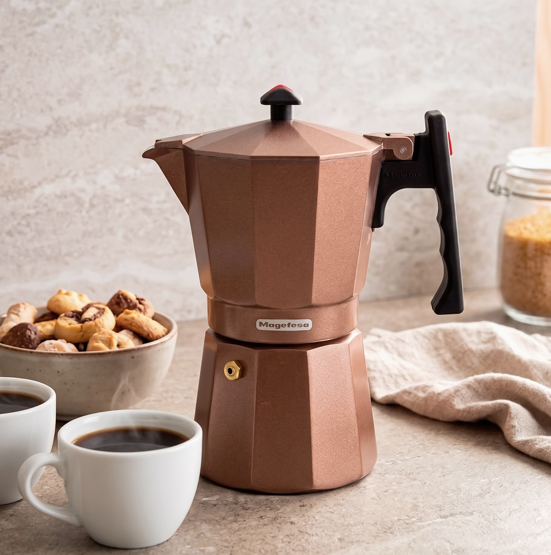 Magefesa Colombia brown 6-cup stovetop espresso maker displayed with coffee cups on a kitchen counter