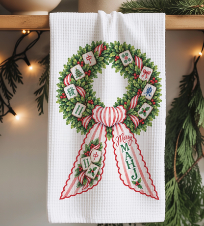 Merry MAHJ Christmas waffle weave kitchen towel featuring a holiday greenery wreath decorated with Mahjong tiles, red berries and striped ribbon