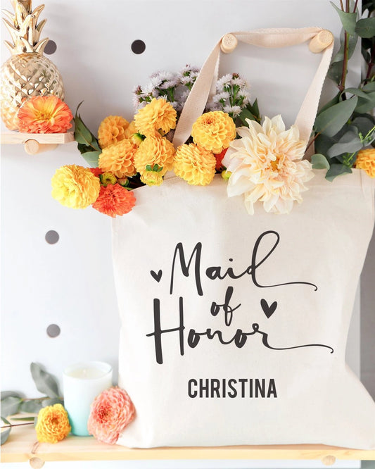 Tote bag with 'Mail of Honor Christina' text, surrounded by flowers and decorative items.