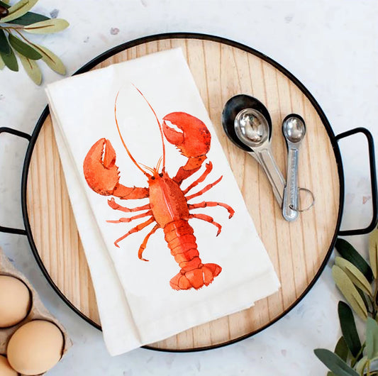 Lobster-themed kitchen towel on a wooden board with measuring spoons and eggs.