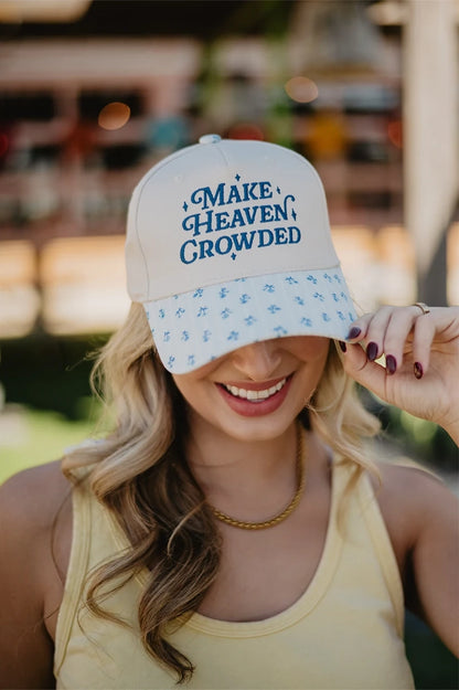 Woman wearing a white cap with blue text and patterns, outdoors.