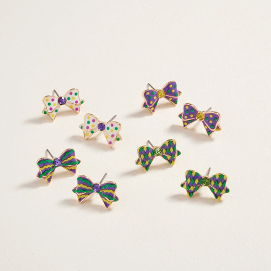 Set of colorful bow-shaped earrings on a light beige background