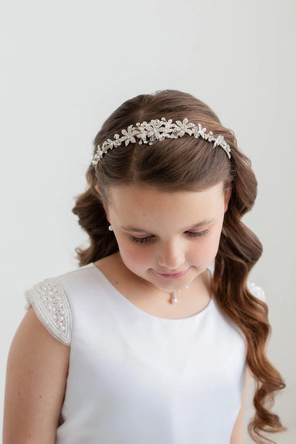 Young girl wearing a decorative headband with a plain background