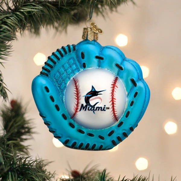 Blue baseball glove ornament with a ball inside, featuring the Miami Marlins logo, hanging on a Christmas tree.