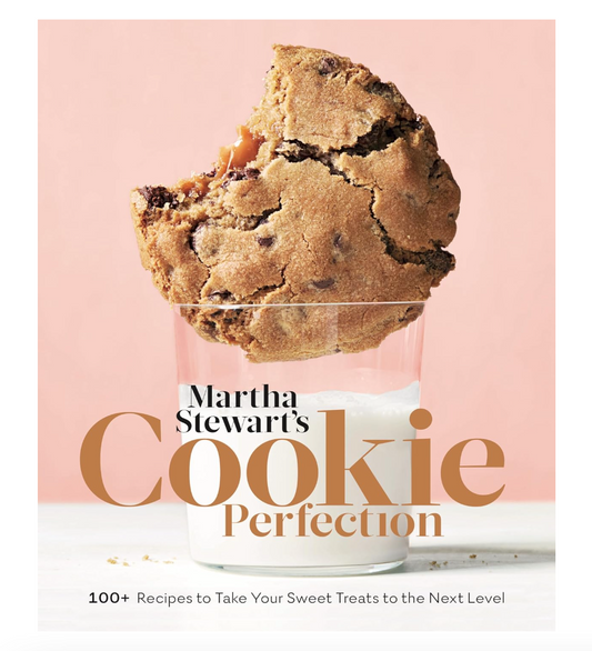 Book cover of 'Cookie Perfection' by Martha Stewart with a cookie and glass of milk on a pink background.