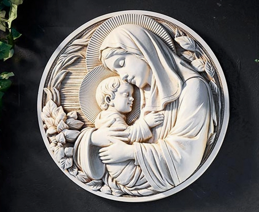 Carved relief of a mother holding a child against a dark background