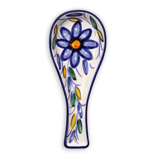 A ceramic spoon rest with a traditional hand-painted floral design, featuring a large blue flower with a yellow center and green and yellow leaves on a white background, isolated on a white backdrop.