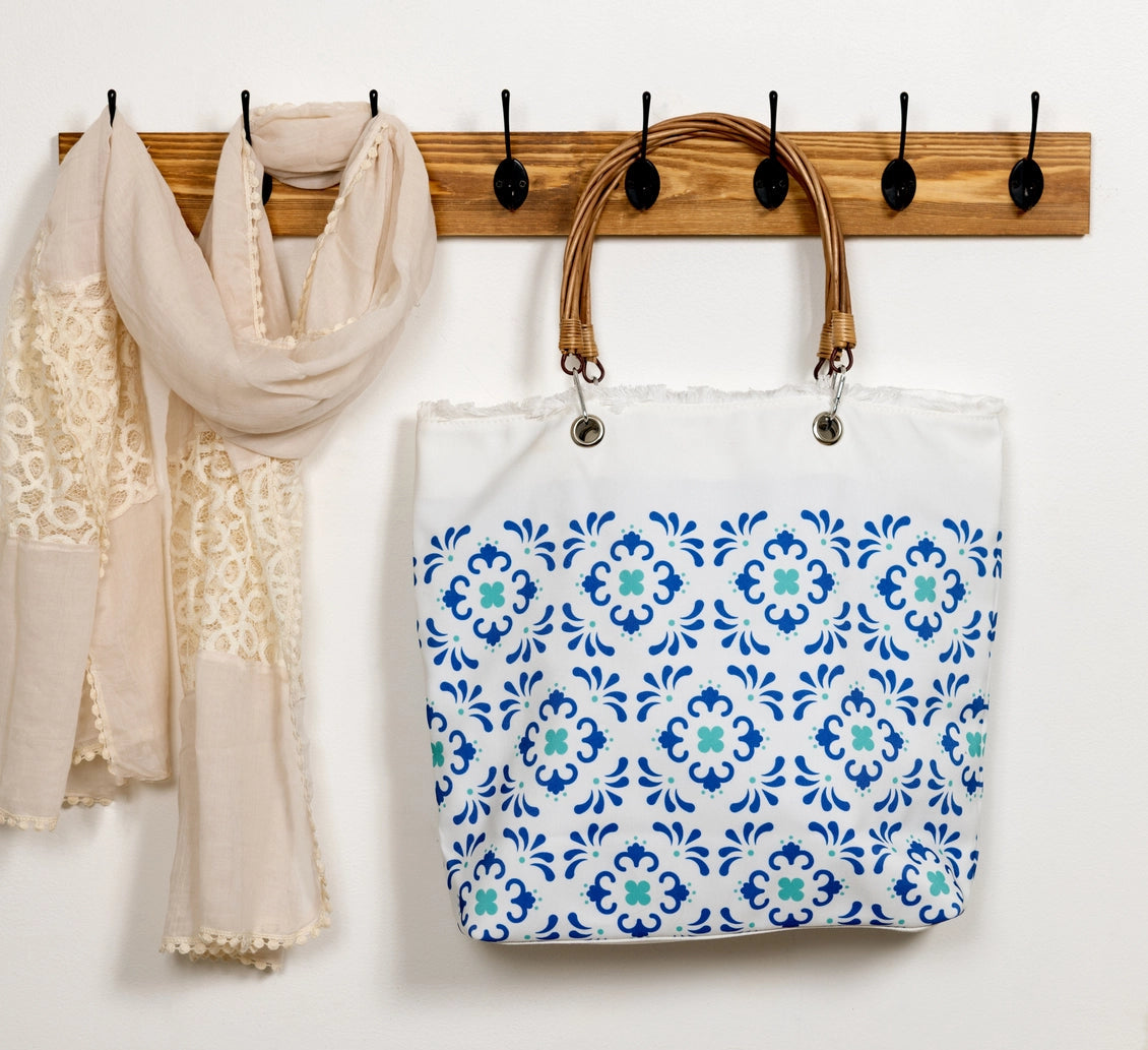 Tote bag with blue floral pattern hanging on a wooden rack with hooks.