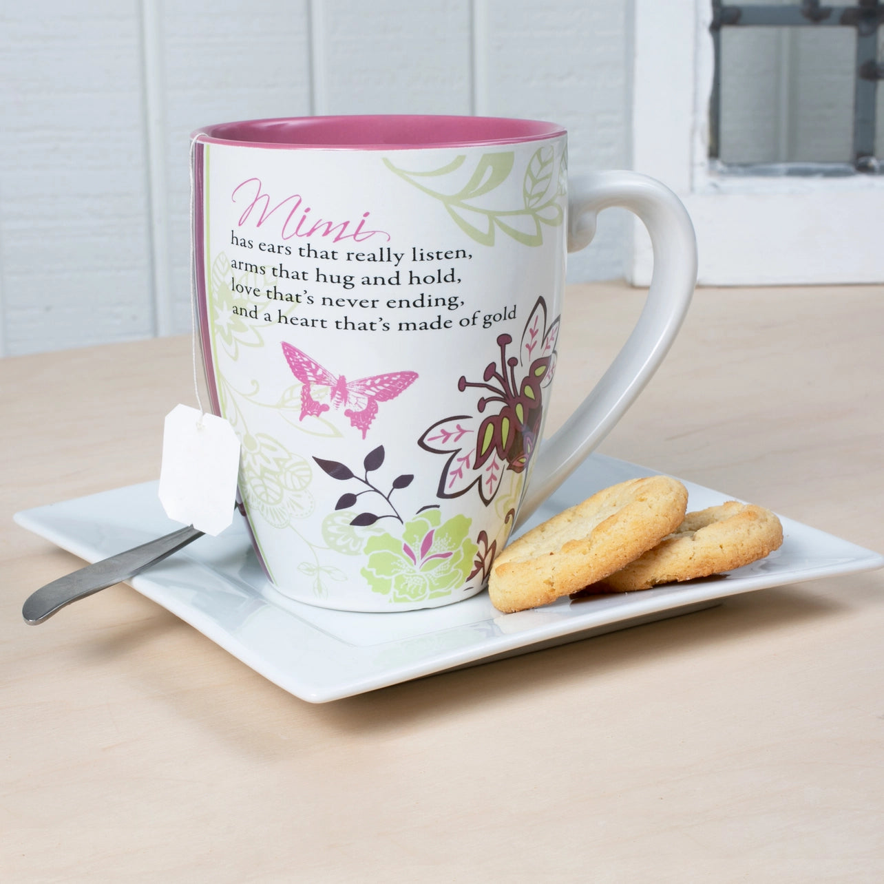 Decorative mug with butterfly design on a plate with cookies and a spoon.