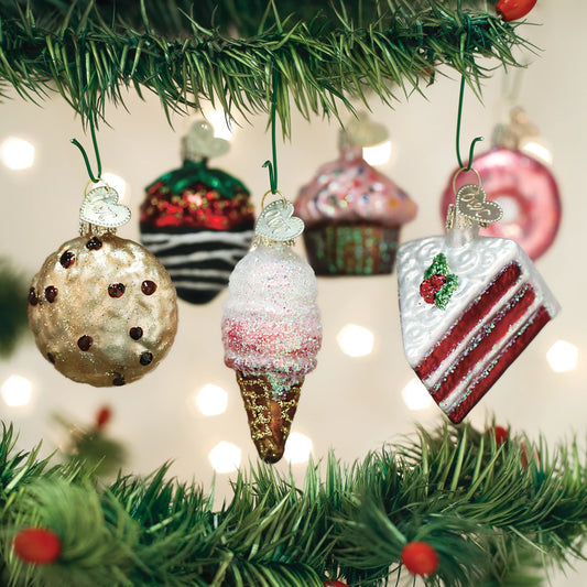 Decorative Christmas ornaments shaped like a cookie, ice cream cone, and cake hanging on a tree.