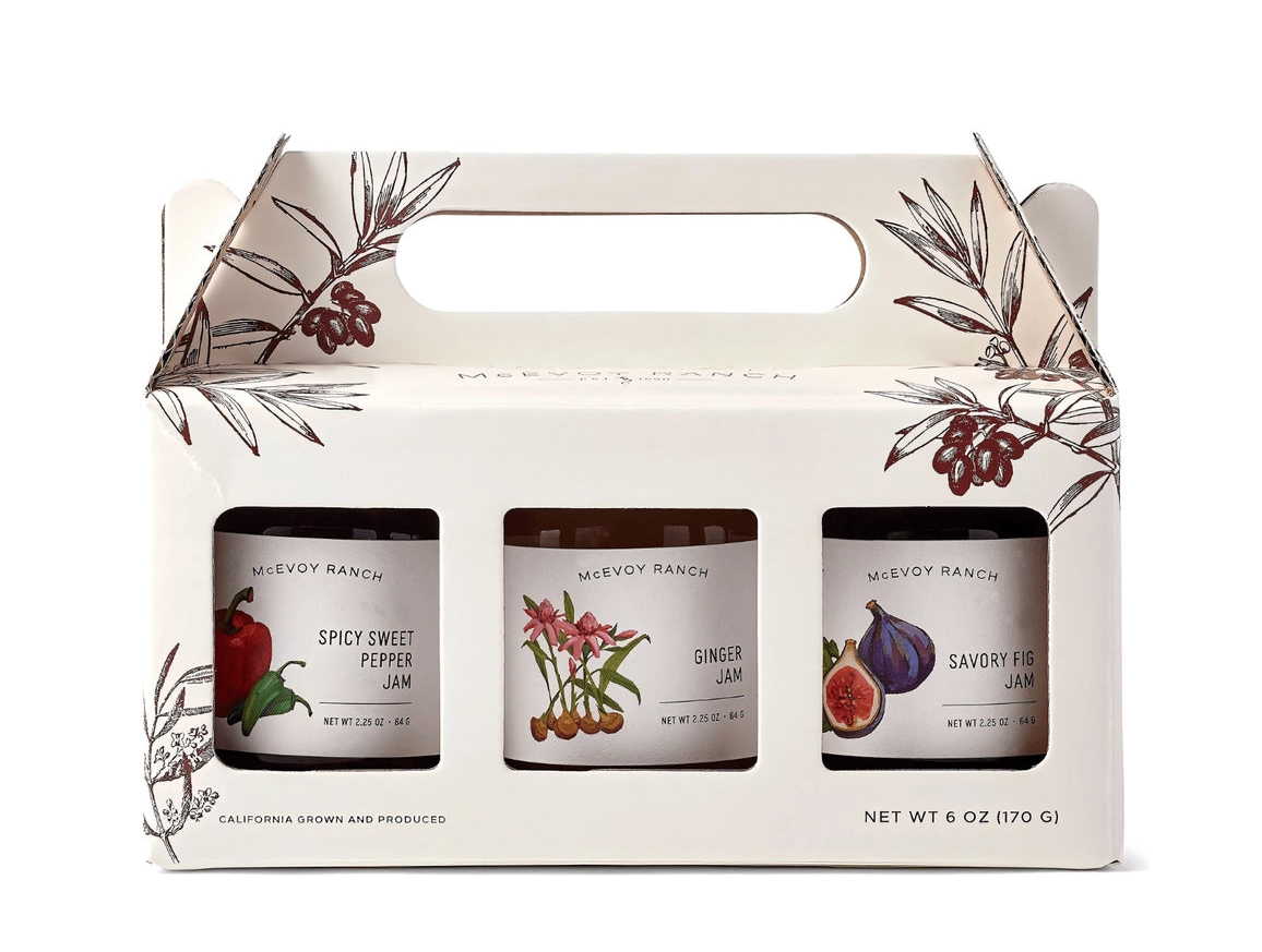 Three jars of Mcevoy Ranch jams in a decorative box with floral designs on a white background.
