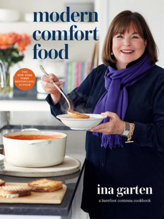 Book cover of 'Modern Comfort Food' by Ina Garten featuring a woman holding a bowl of food.