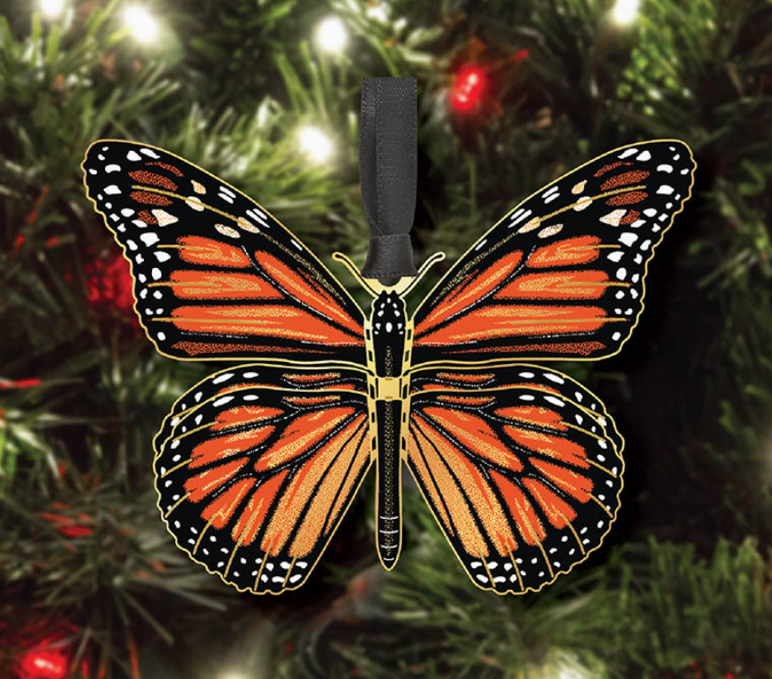 Butterfly-shaped ornament on a Christmas tree with lights and red berries.