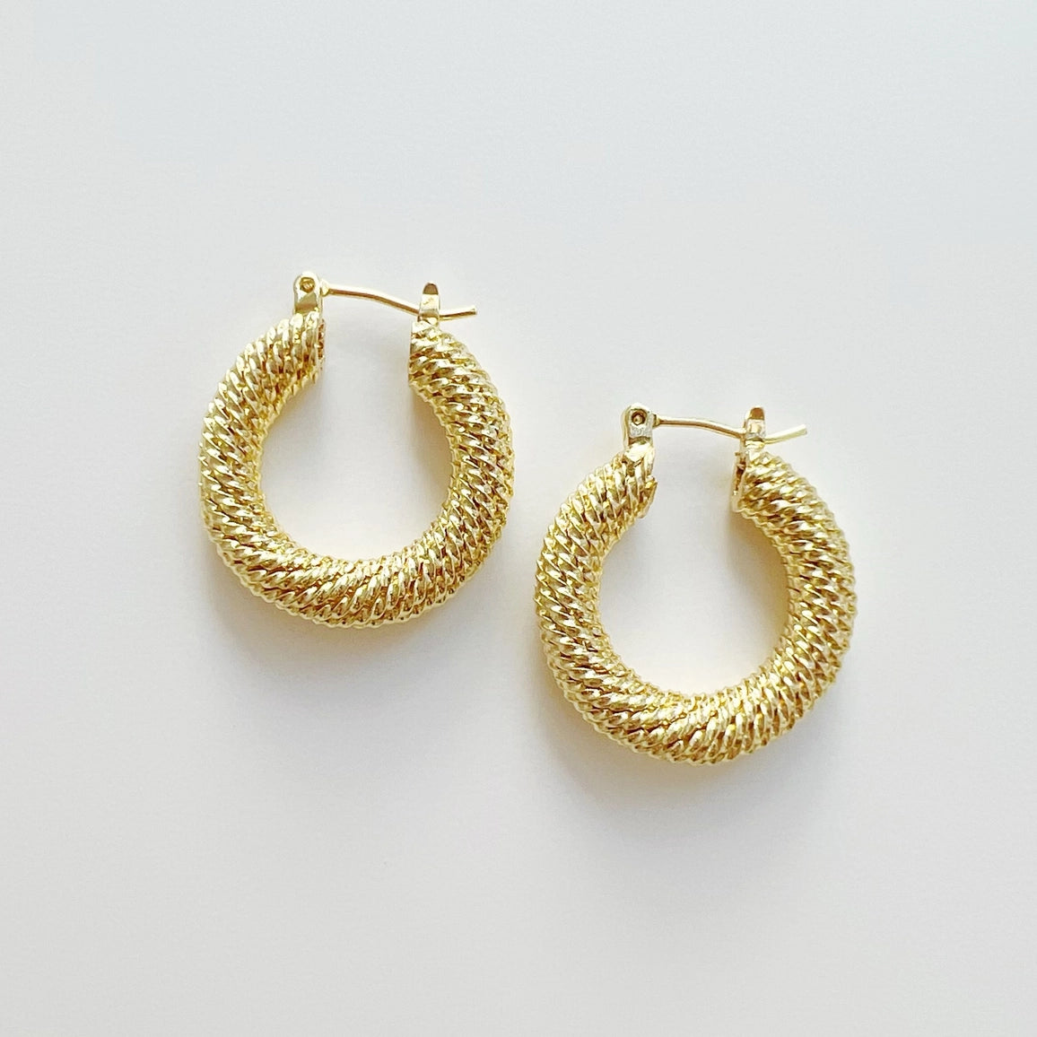 Gold hoop earrings on a light gray background