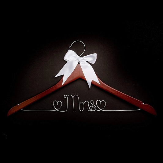 Wooden hanger with a white bow and 'Mrs.' inscription on a black background