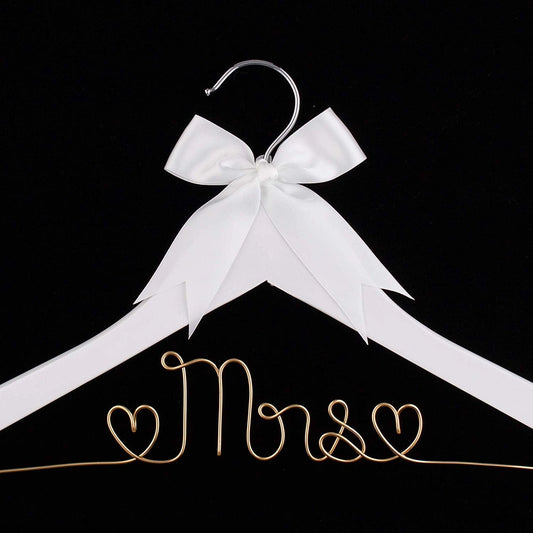 White hanger with a gold 'Mrs.' inscription and a white bow on a black background