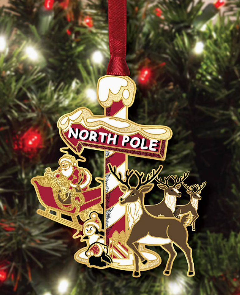 Christmas ornament with Santa Claus, reindeer, and 'North Pole' text on a tree.