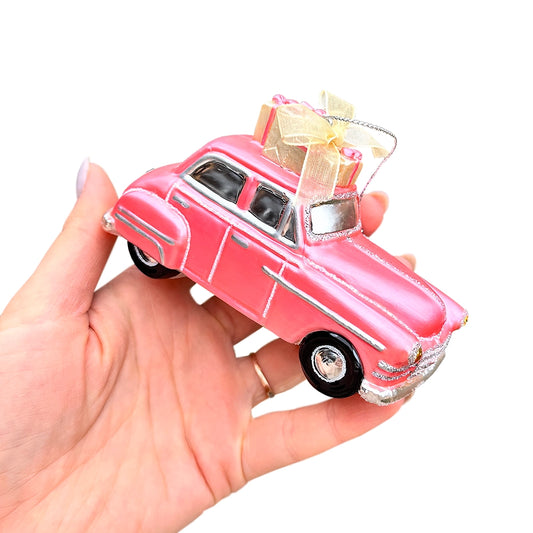Pink vintage car model with a gift box on a white background