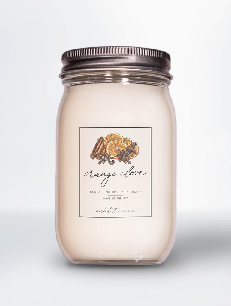 Market Street Candle Co. Orange Clove 16 oz soy candle displayed with fresh oranges, cinnamon sticks and cloves.