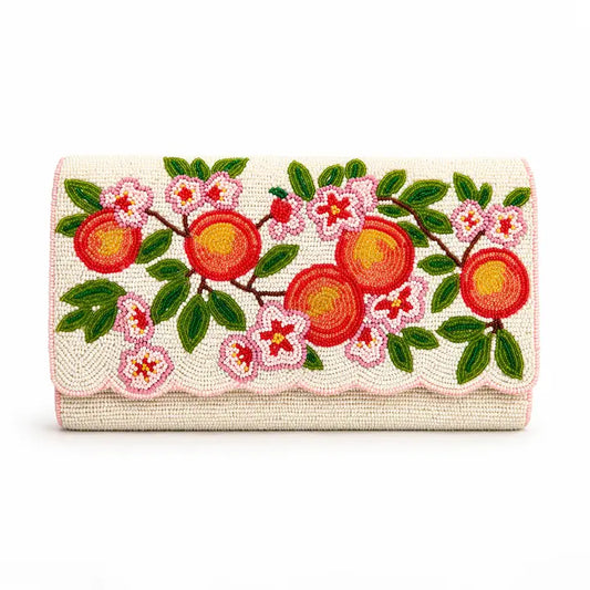 A rectangular clutch bag with a scalloped edge, featuring a vibrant embroidered design of red peaches, pink blossoms, and green leaves on a cream-colored woven background. NY Gift Boutique