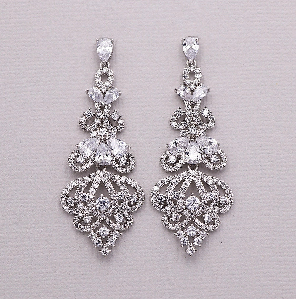 Pair of silver earrings with clear gemstones on a light gray background