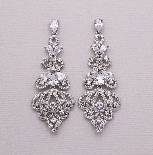 Pair of silver earrings with clear gemstones on a light gray background
