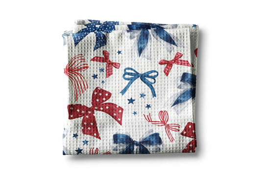 Waffle-textured blanket with red, blue, and white bows and star patterns on a white background