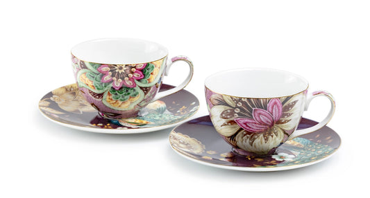 Two ceramic teacups with floral designs on saucers against a white background