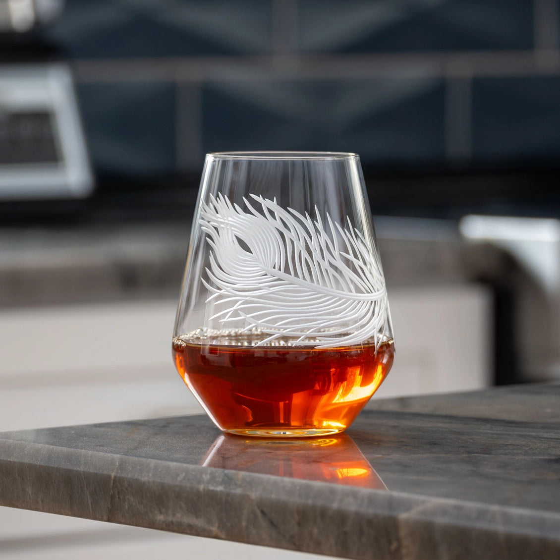 Etched glass with amber liquid on a marble surface