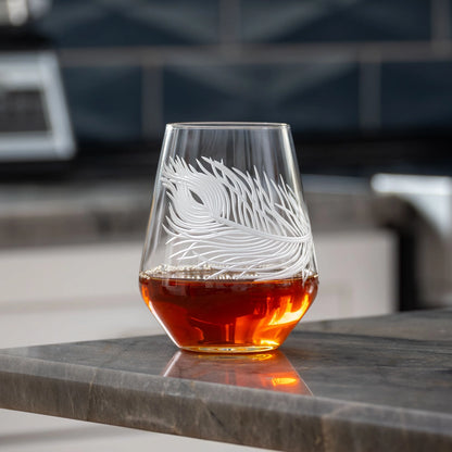 Etched glass with amber liquid on a marble surface