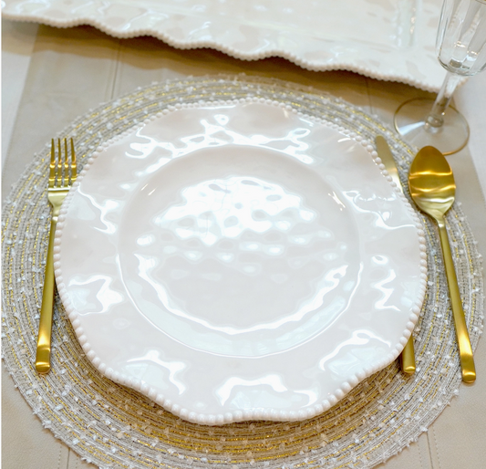 Perlette cream melamine dinner plate with beaded ruffled rim styled with gold flatware and decorative charger