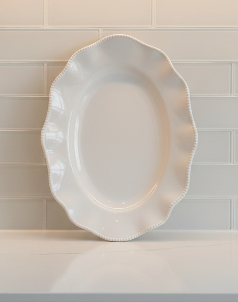 Perlette Cream 18-inch melamine oval serving platter displayed upright with scalloped shape and beaded rim