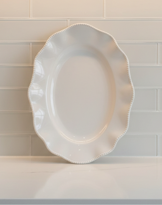 Perlette Cream 18-inch melamine oval serving platter displayed upright with scalloped shape and beaded rim