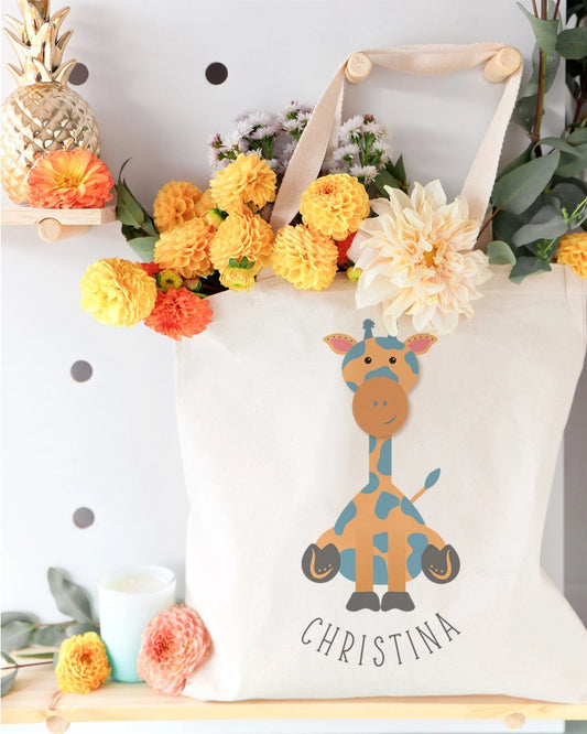 White tote bag with a giraffe design and 'Christina' text, surrounded by flowers and decorative items.