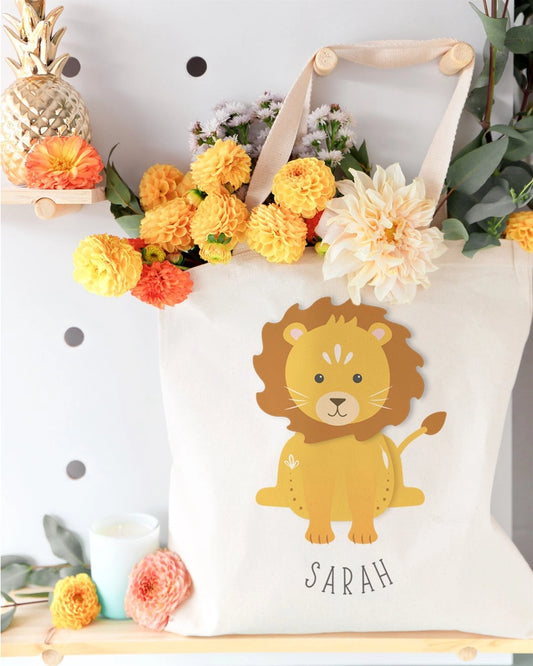 White tote bag with a lion design and 'Sarah' text, surrounded by flowers and decorative items.
