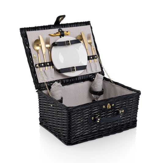 Black wicker picnic basket with cutlery and plates on a white background