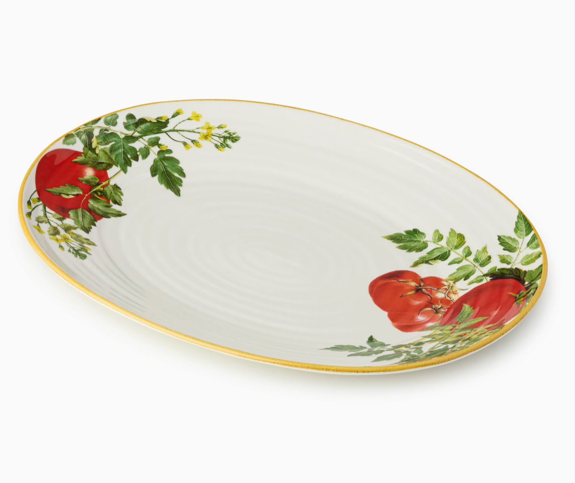 Oval ceramic platter with tomato and leaf design on a white background