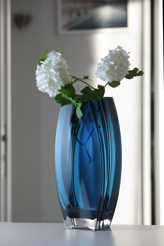 Blue glass vase with white flowers on a blurred background
