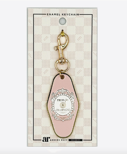 Press for Champagne Mahjong enamel keychain charm by Anders Ruff in blush pink with ornate medallion and gold-tone lobster clasp.