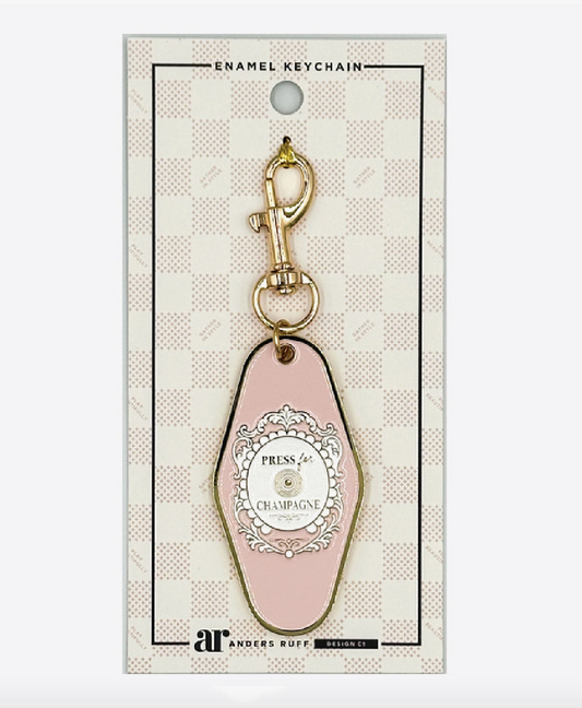 Press for Champagne Mahjong enamel keychain charm by Anders Ruff in blush pink with ornate medallion and gold-tone lobster clasp.