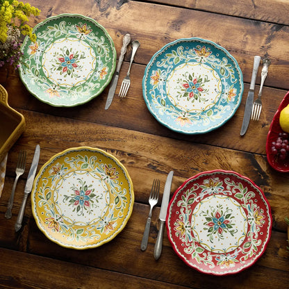 Four colorful ceramic plates with floral patterns on a wooden table with cutlery.