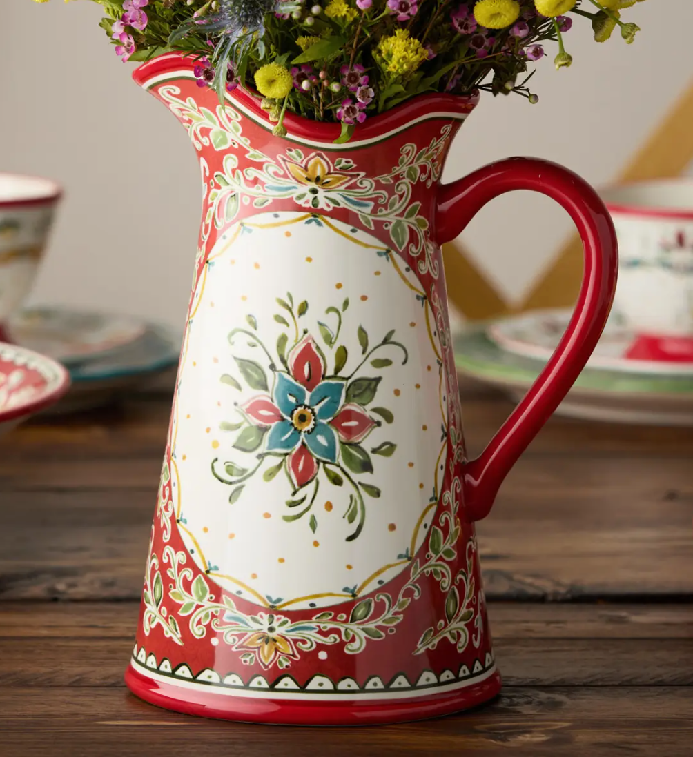 Decorative ceramic pitcher with floral design on a wooden surface